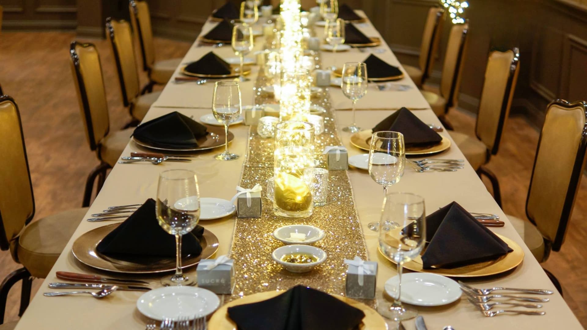 Long banquet table set with gold chargers and candles